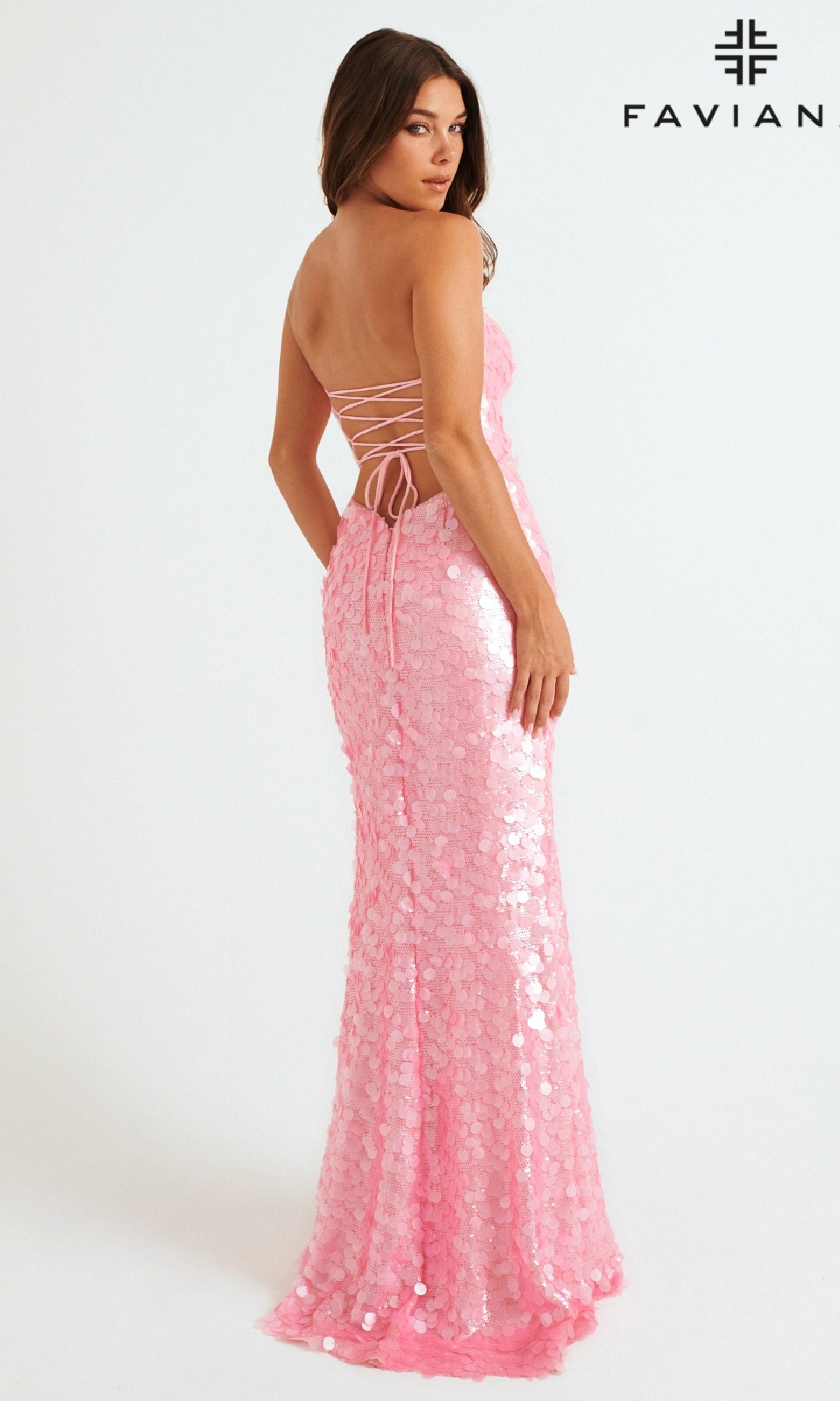 A woman stands sideways against a plain white background, modeling the Faviana 11258 long prom dress—strapless, covered in sequins, and featuring a lace-up back. The word